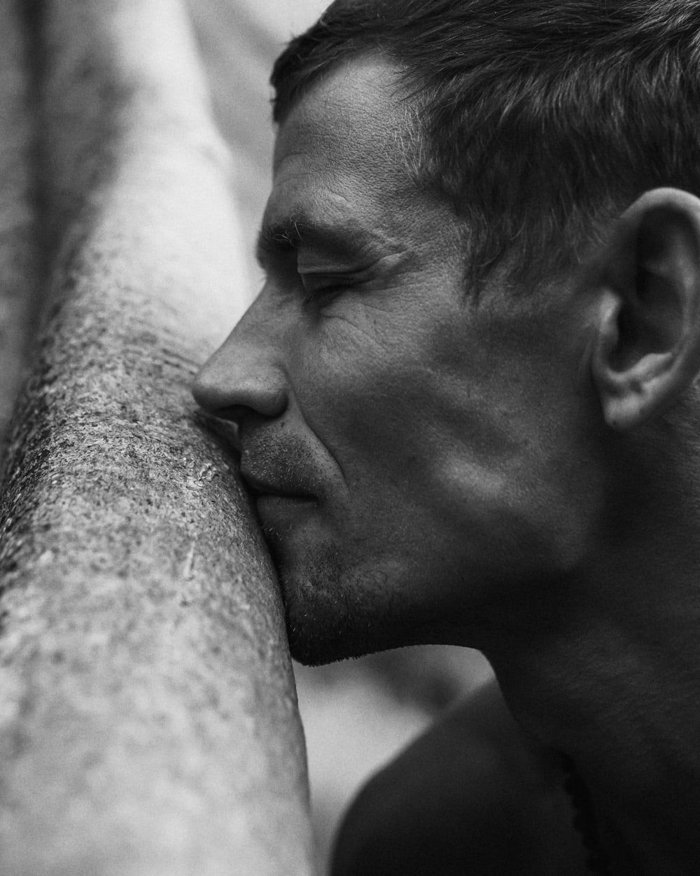 Alexander Korol, founder of WAO, eyes closed, his cheek against the bark of a tree.